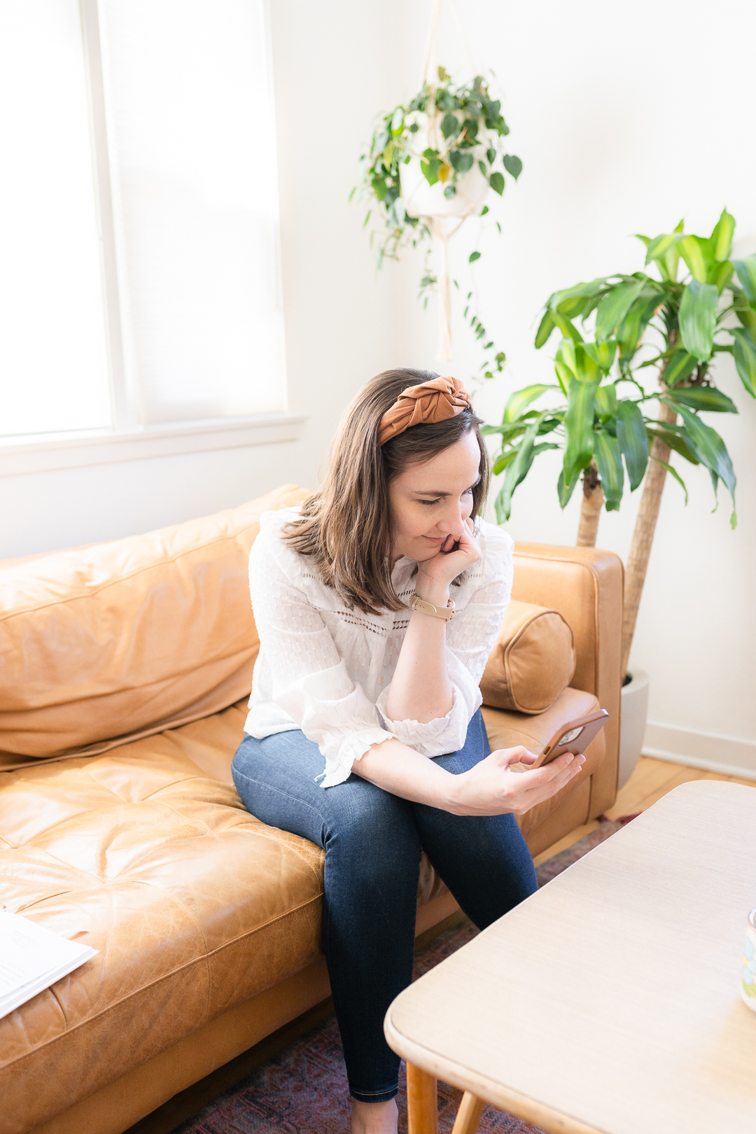 Woman sitting on couch scrolling phone
